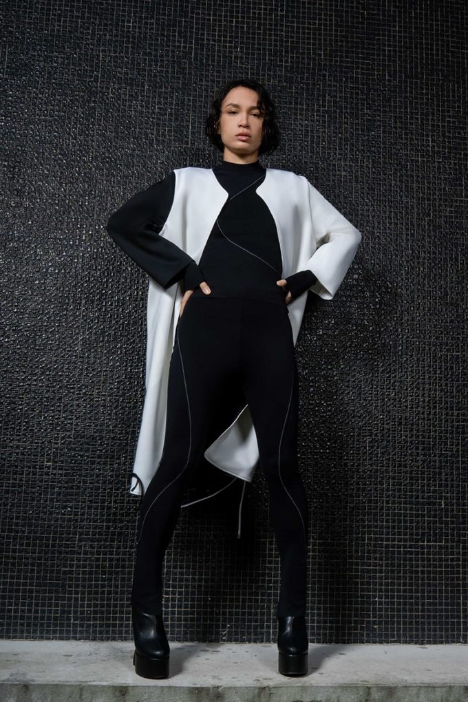 white neoprene long coat with two-tone black and white sleeves on a female model.